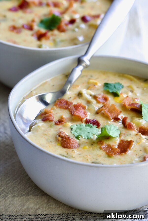 A beautifully presented bowl of Roasted Poblano Corn Chowder, garnished with fresh cilantro sprigs, showcasing its rich texture.