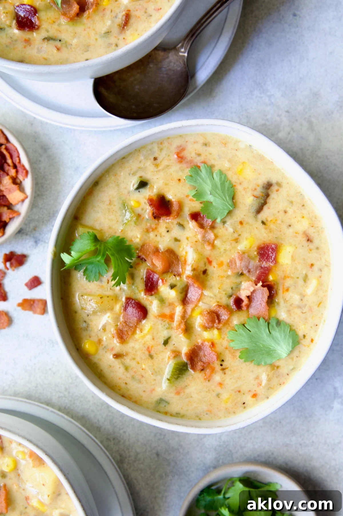 A single white bowl of Roasted Poblano Corn Chowder beautifully garnished with fresh cilantro sprigs, highlighting the vibrant colors of the soup.