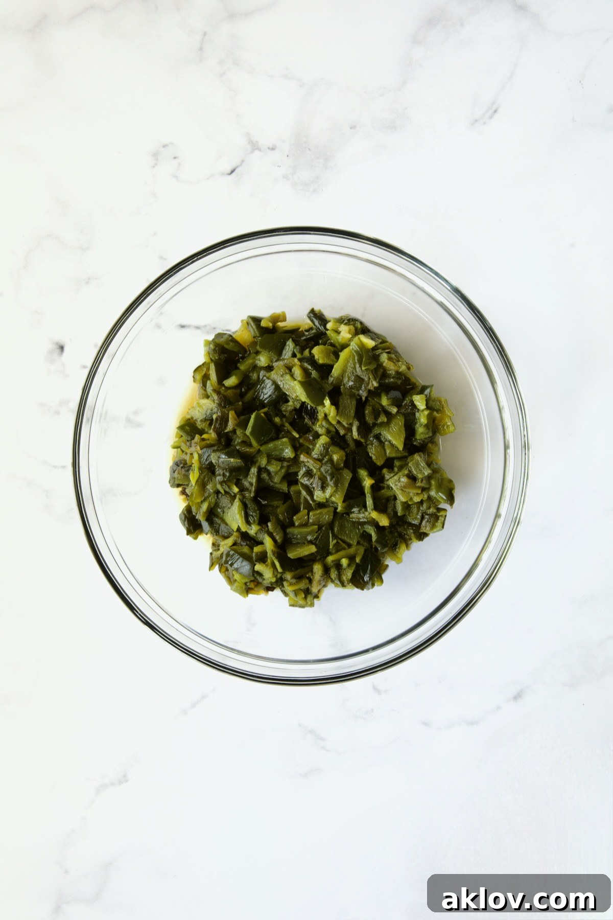 A glass bowl filled with finely chopped, roasted poblano peppers, ready to be added to the chowder.