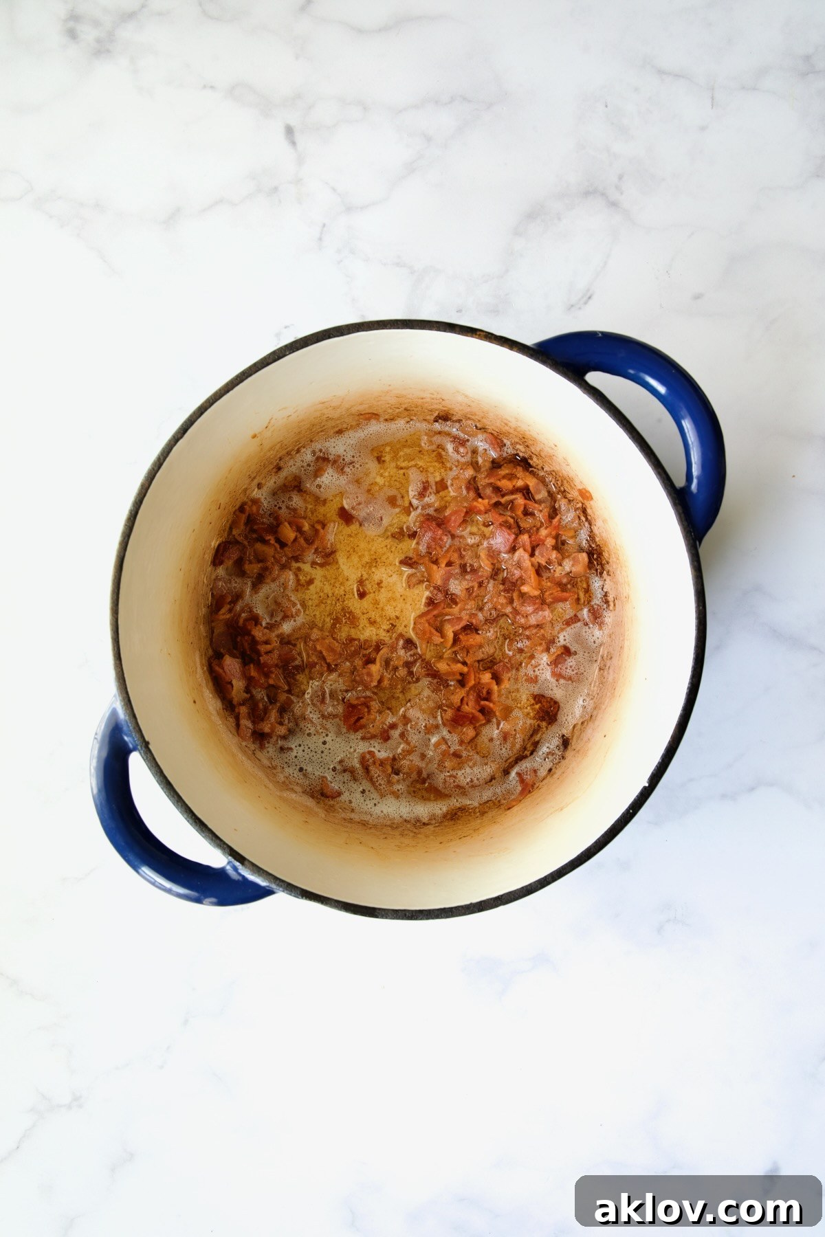 Crispy, golden-brown bacon pieces resting in a vibrant blue Dutch oven, having just been cooked.
