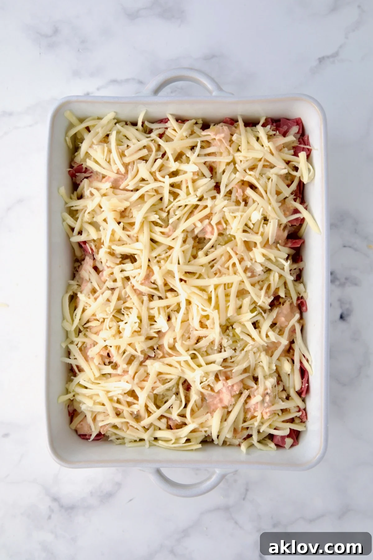 Creamy Reuben Comfort Casserole 15 The last layer of shredded Swiss cheese covering the Reuben Casserole, preparing for its melt.