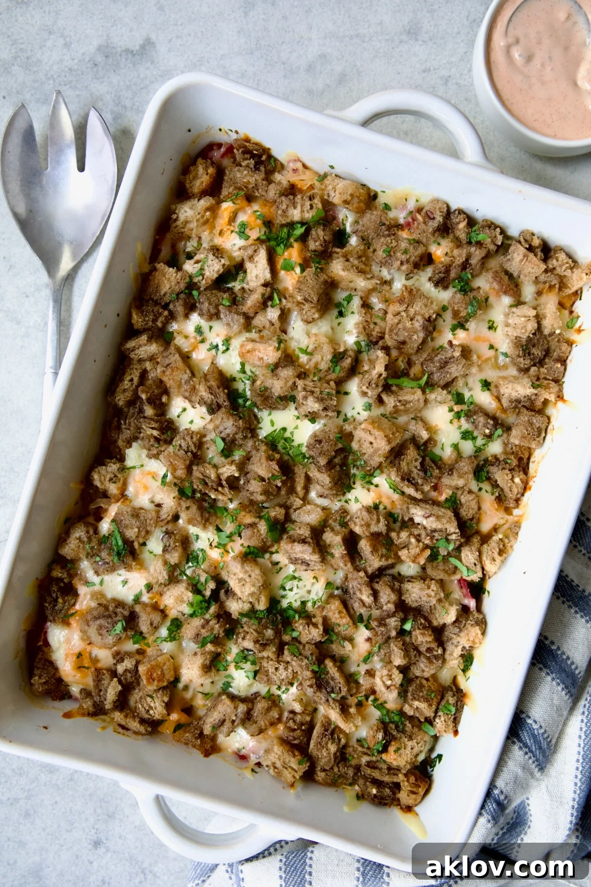 Creamy Reuben Comfort Casserole 17 A perfectly baked Reuben Casserole, golden and bubbling, in a white rectangular baking dish, elegantly garnished with fresh chopped parsley.