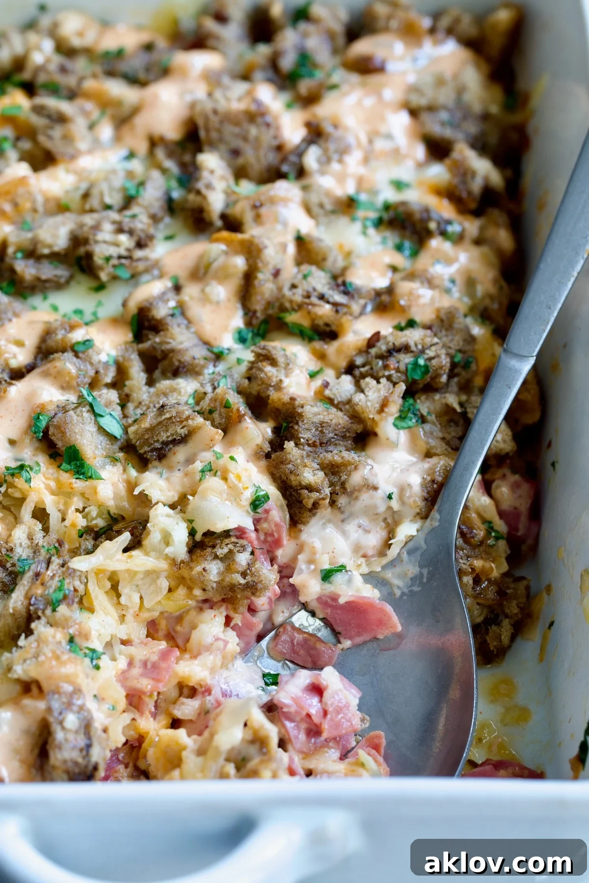 Creamy Reuben Comfort Casserole 19 A close-up shot of the perfectly baked Reuben Casserole in its white rectangular dish, with a serving spoon resting inside, highlighting its tempting layers.