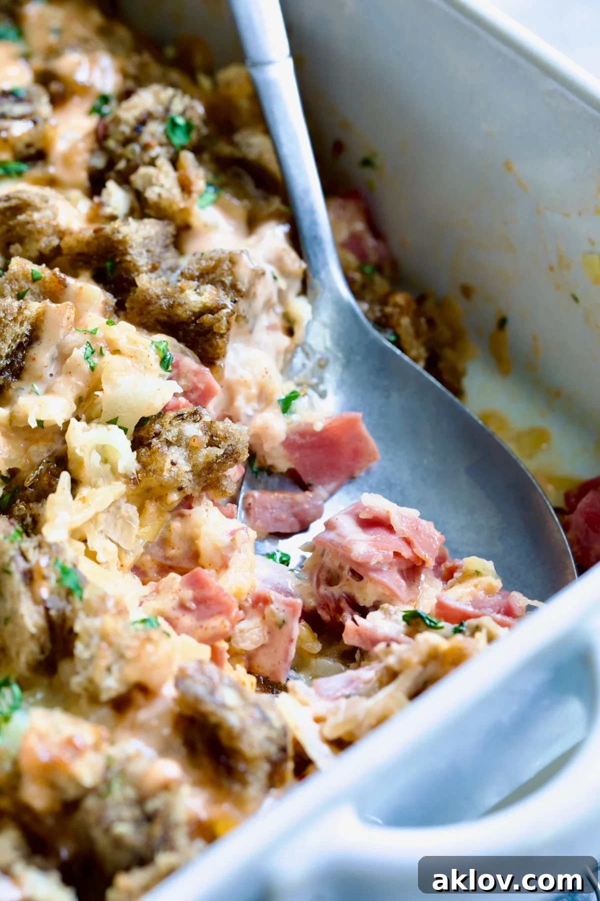 Creamy Reuben Comfort Casserole 3 A metal serving spoon carefully dishing out a generous portion of the Reuben Casserole from the baking dish.