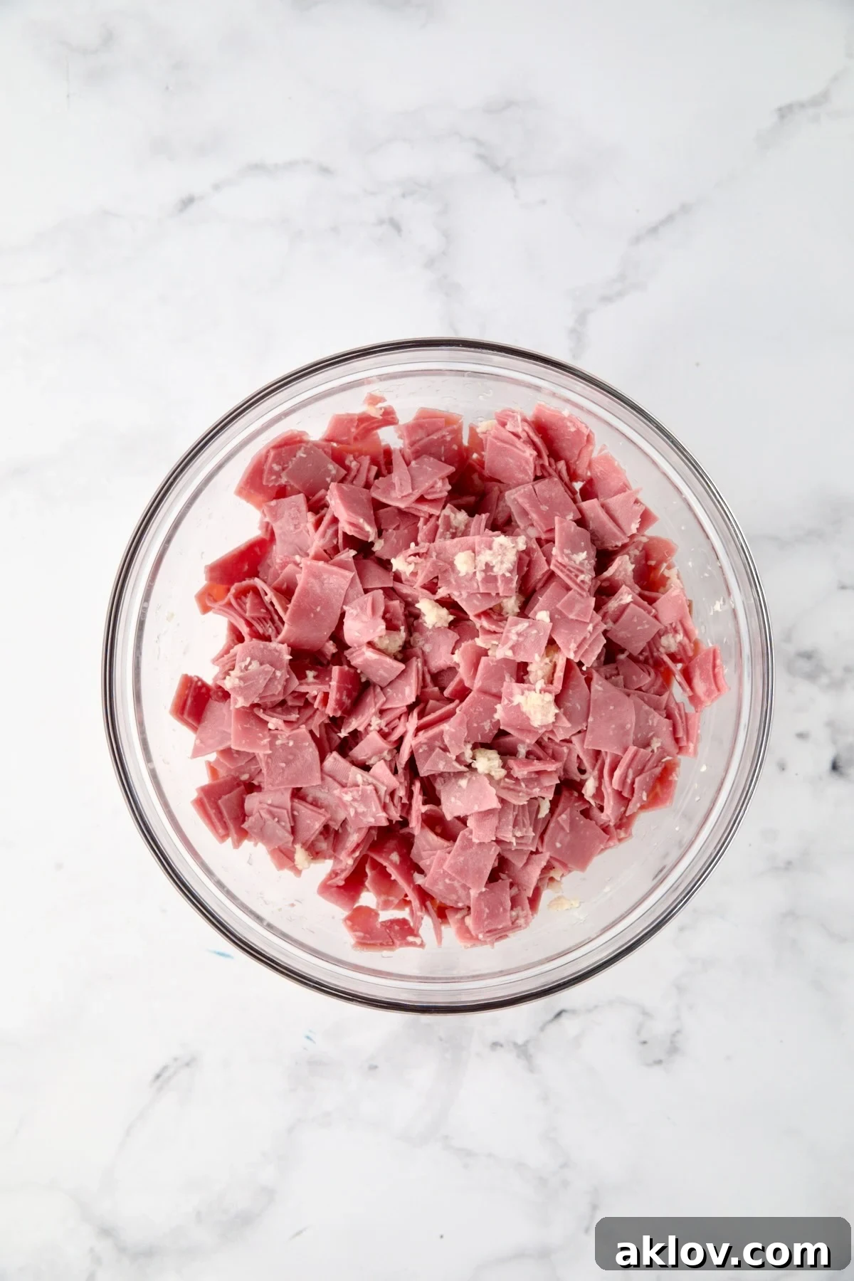 Creamy Reuben Comfort Casserole 7 Chopped corned beef pieces expertly mixed with prepared horseradish in a glass bowl, ready for layering.