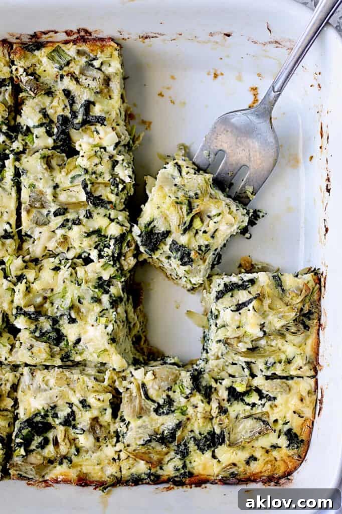 Close-up photo of a Spinach Artichoke Square being served with a fork, highlighting its golden-brown crust and creamy interior.