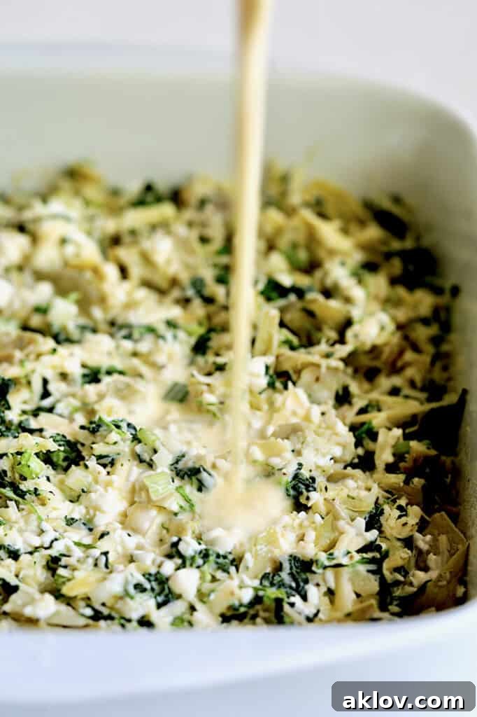Photo of custard combination being poured over spinach artichoke combination.
