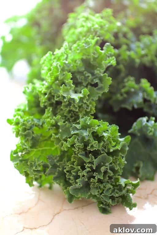 A close-up view of fresh, vibrant green kale leaves, highlighting their texture and rich color, ready to be incorporated into the soup.