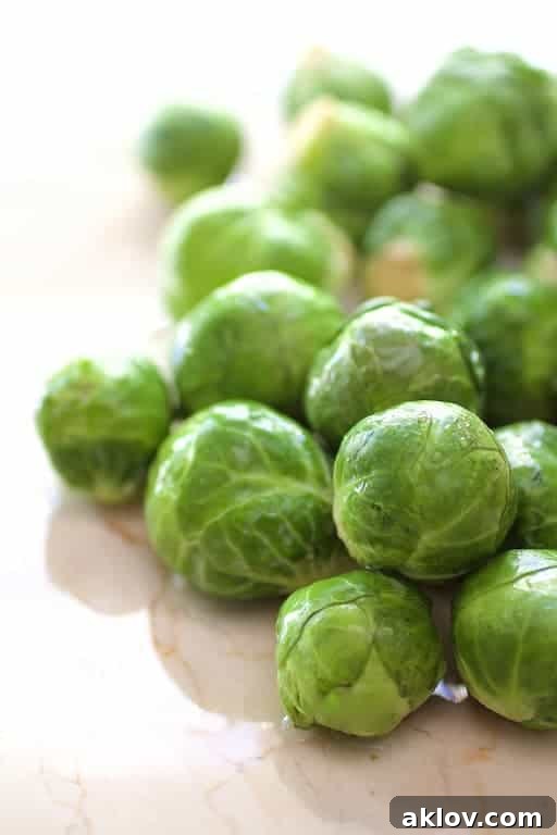 A tight shot of raw Brussels sprouts, their layers and vibrant green color visible, prepared for cooking.
