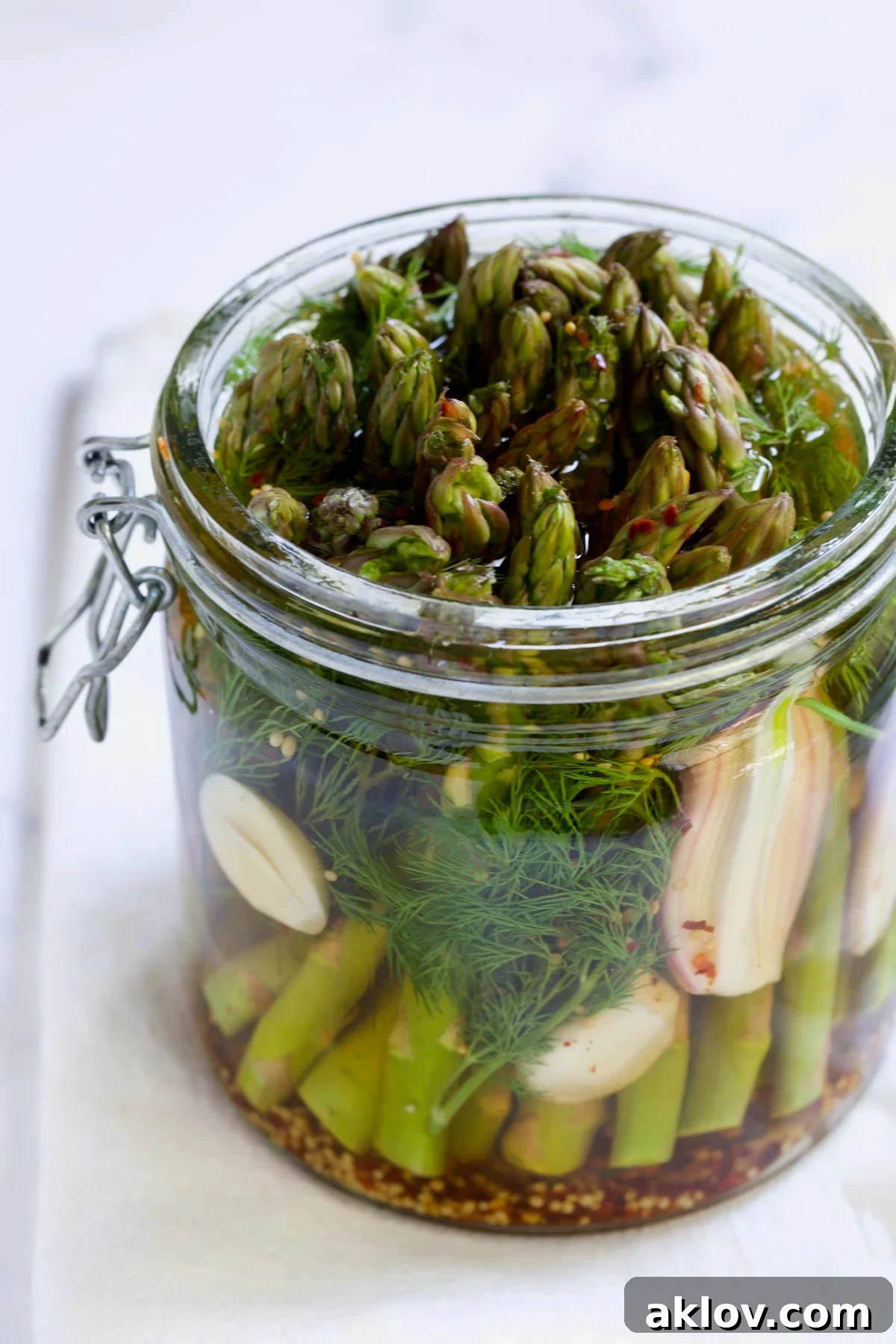 Zesty Pickled Asparagus 11 Two glass jars filled with perfectly homemade pickled asparagus, sealed and ready to be enjoyed or stored.