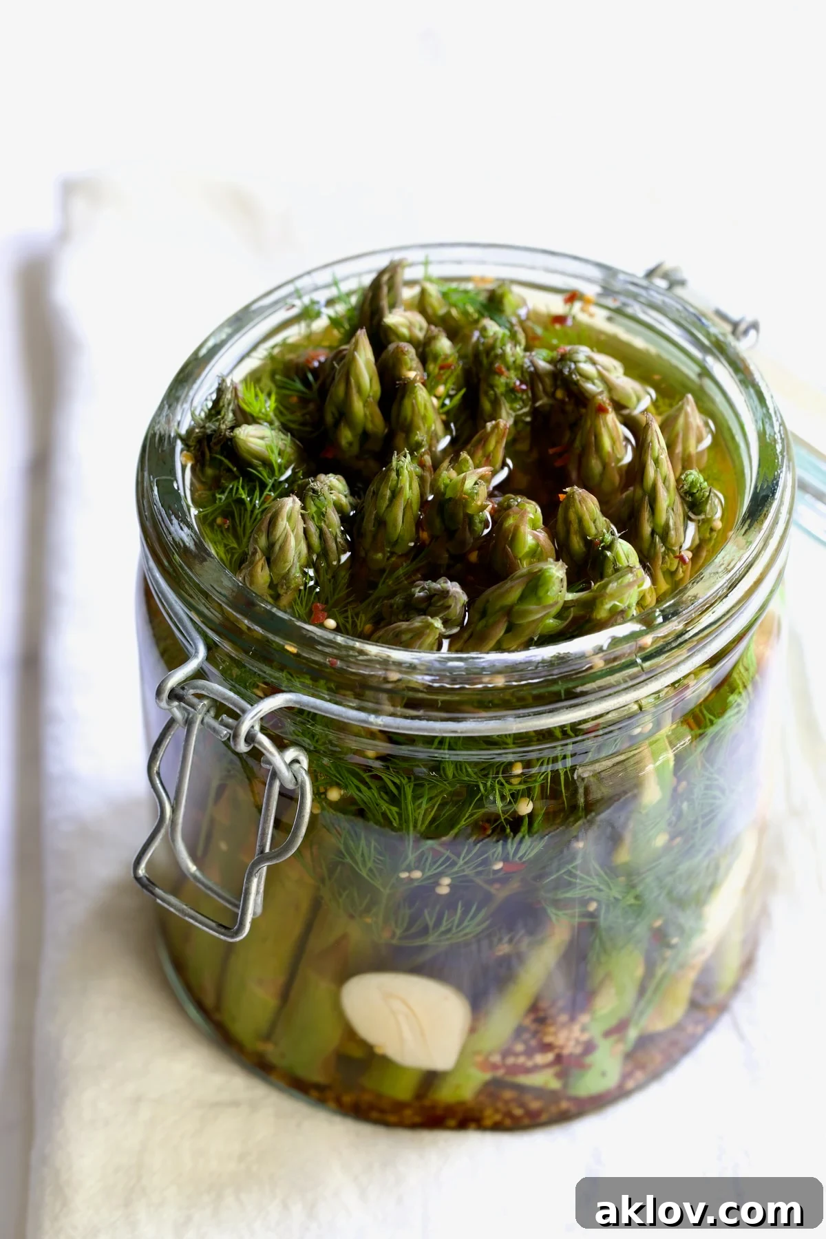 Zesty Pickled Asparagus 10 Close-up view of a glass jar filled with vibrant pickled asparagus, showcasing its characteristic olive green hue and crisp texture submerged in brine.