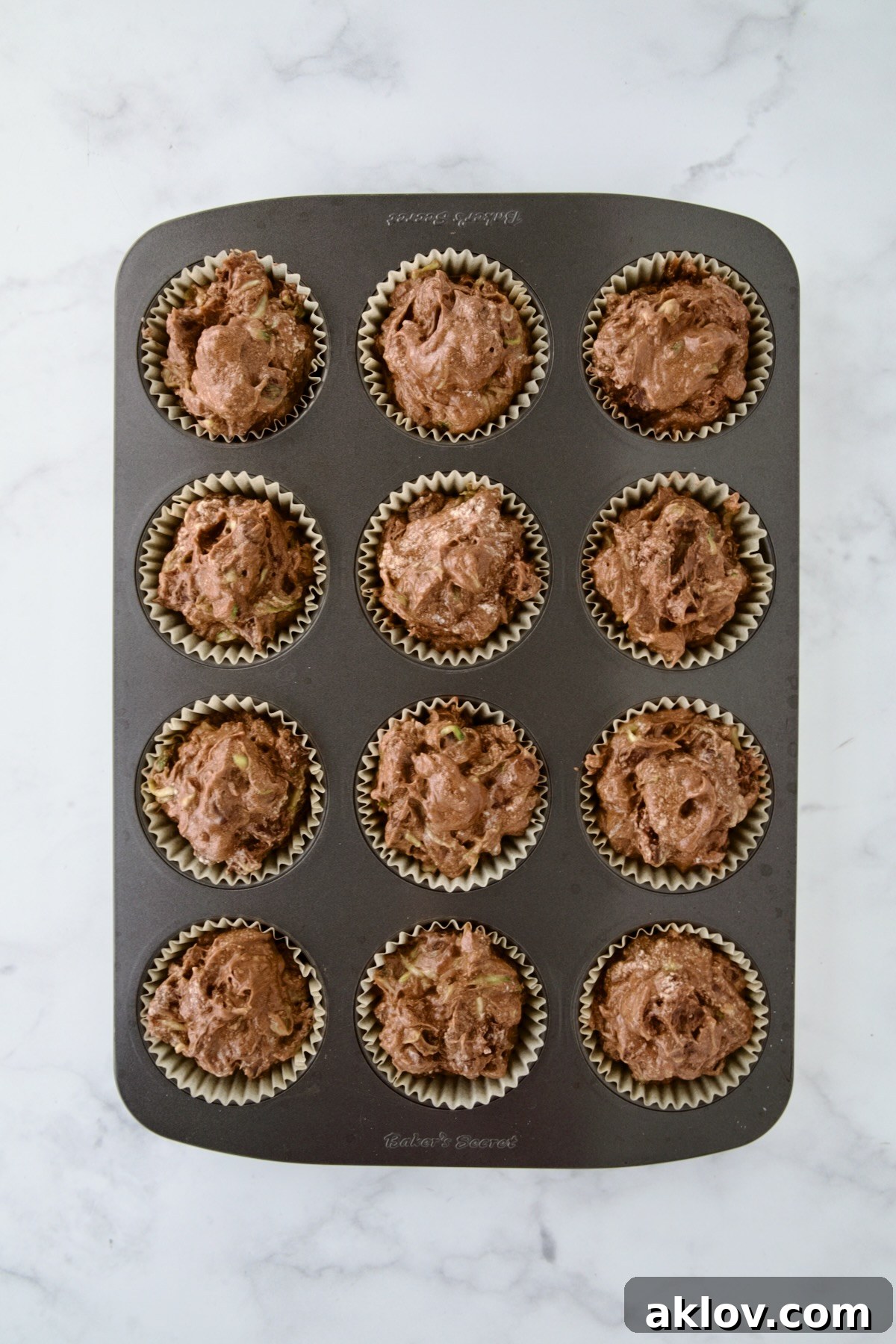 Batter for muffins in 12-cup muffin pan before being baked.