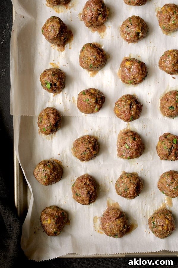 Photo of baked meatballs on parchment paper.