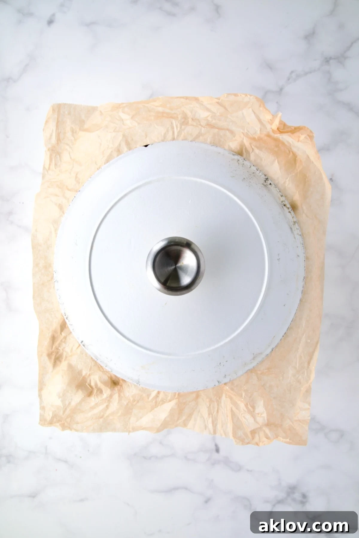 Top down photo showing parchment paper under the cover for a Dutch oven demonstrating how to seal it.