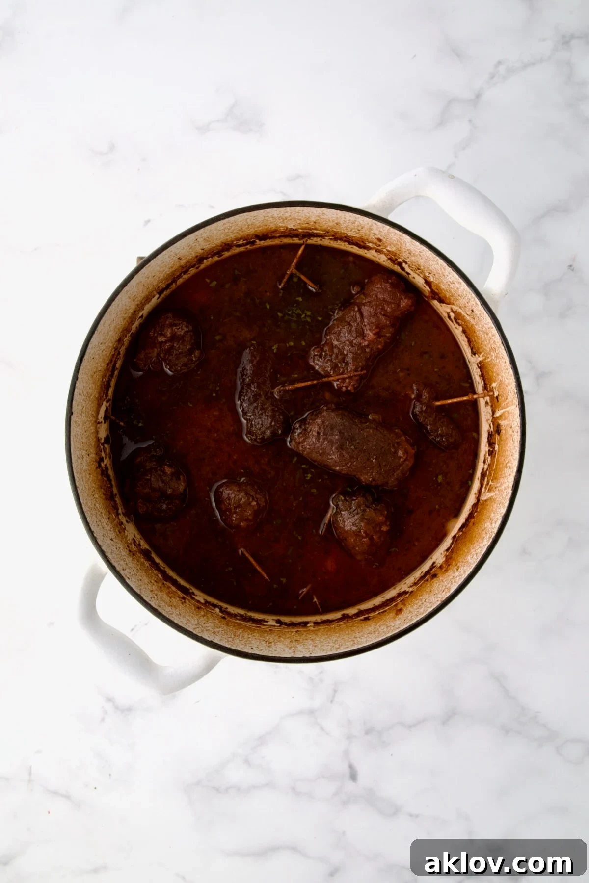 Fully cooked beef rolls in white Dutch oven.