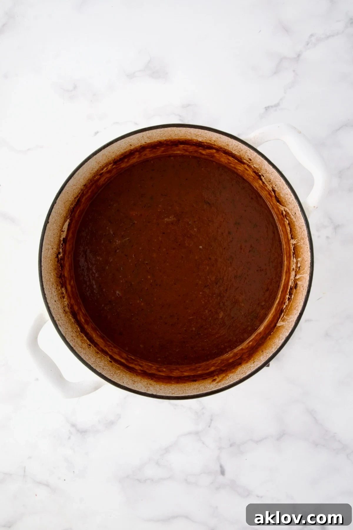 Thickened sauce in white Dutch oven.