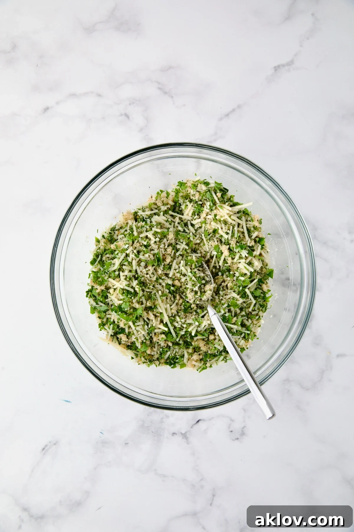 Cheese, breadcrumb, parsley and garlic combination in glass bowl.