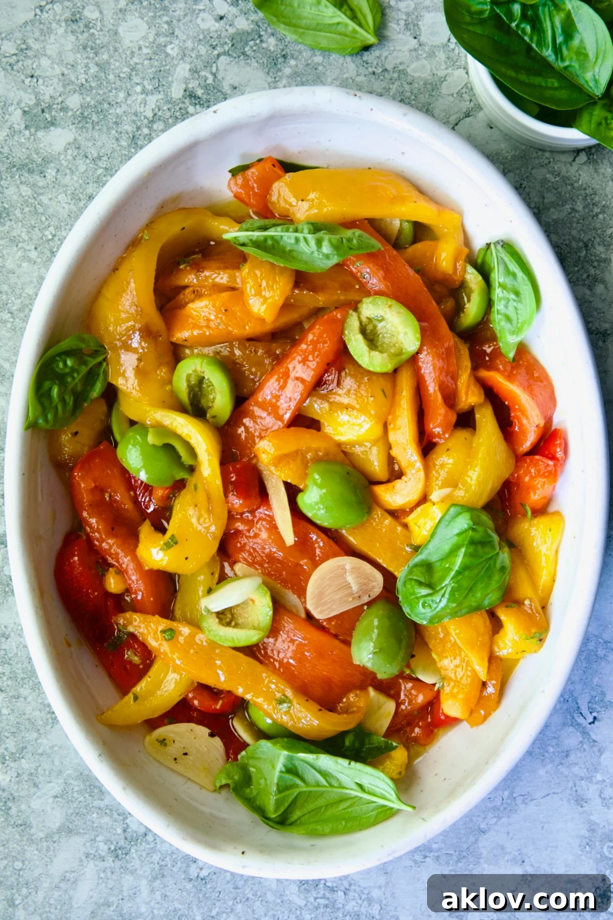 Roasted Pepper Salad in white oval serving bowl garnished with fresh basil leaves.