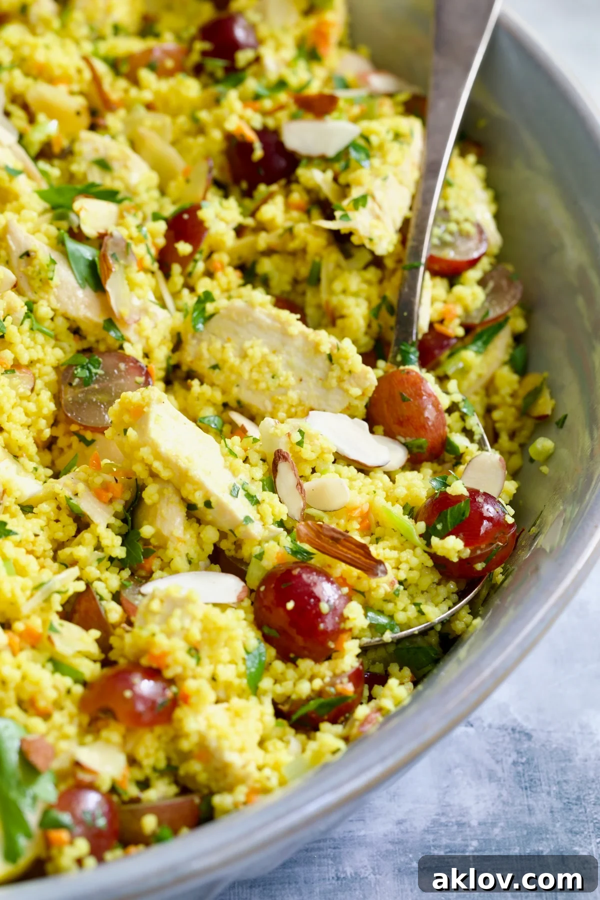 Chicken Couscous Salad in gray bowl with serving spoon.