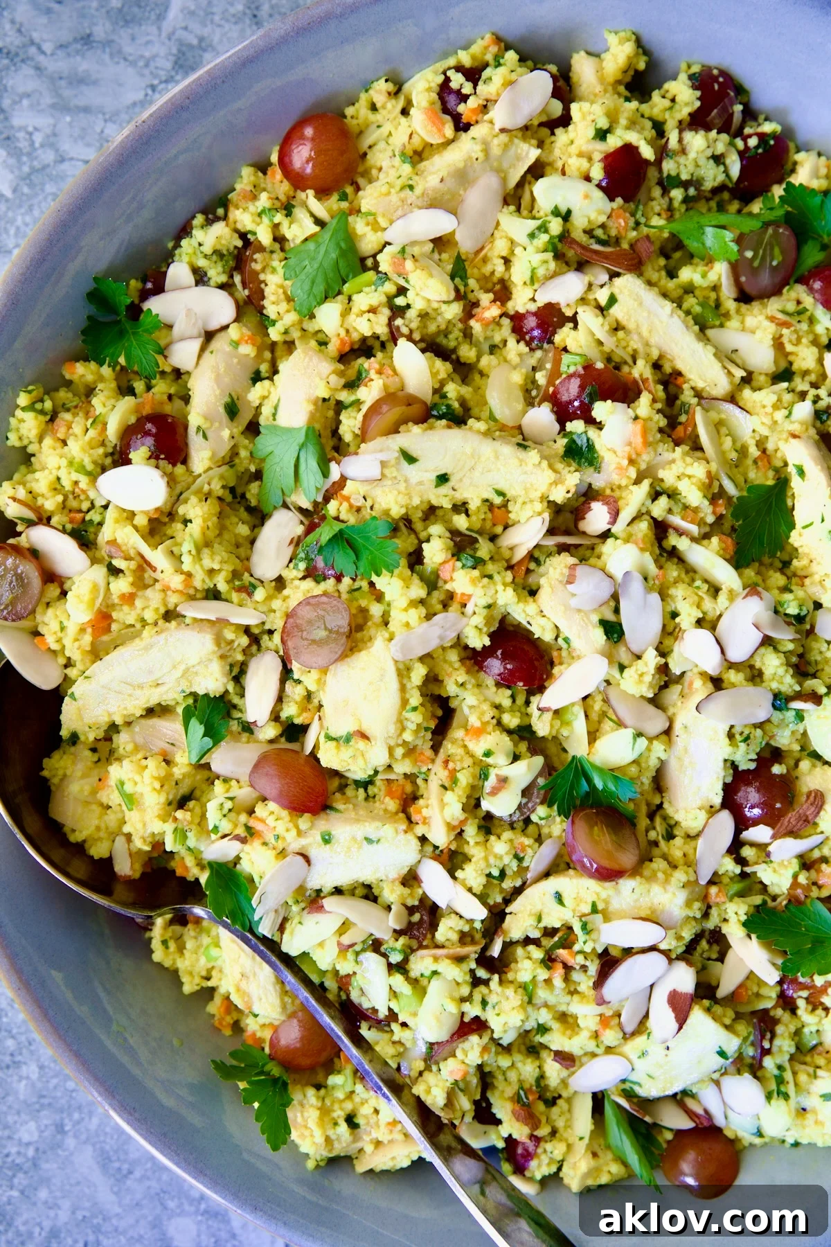 Chicken Couscous Salad in gray bowl with serving spoon.
