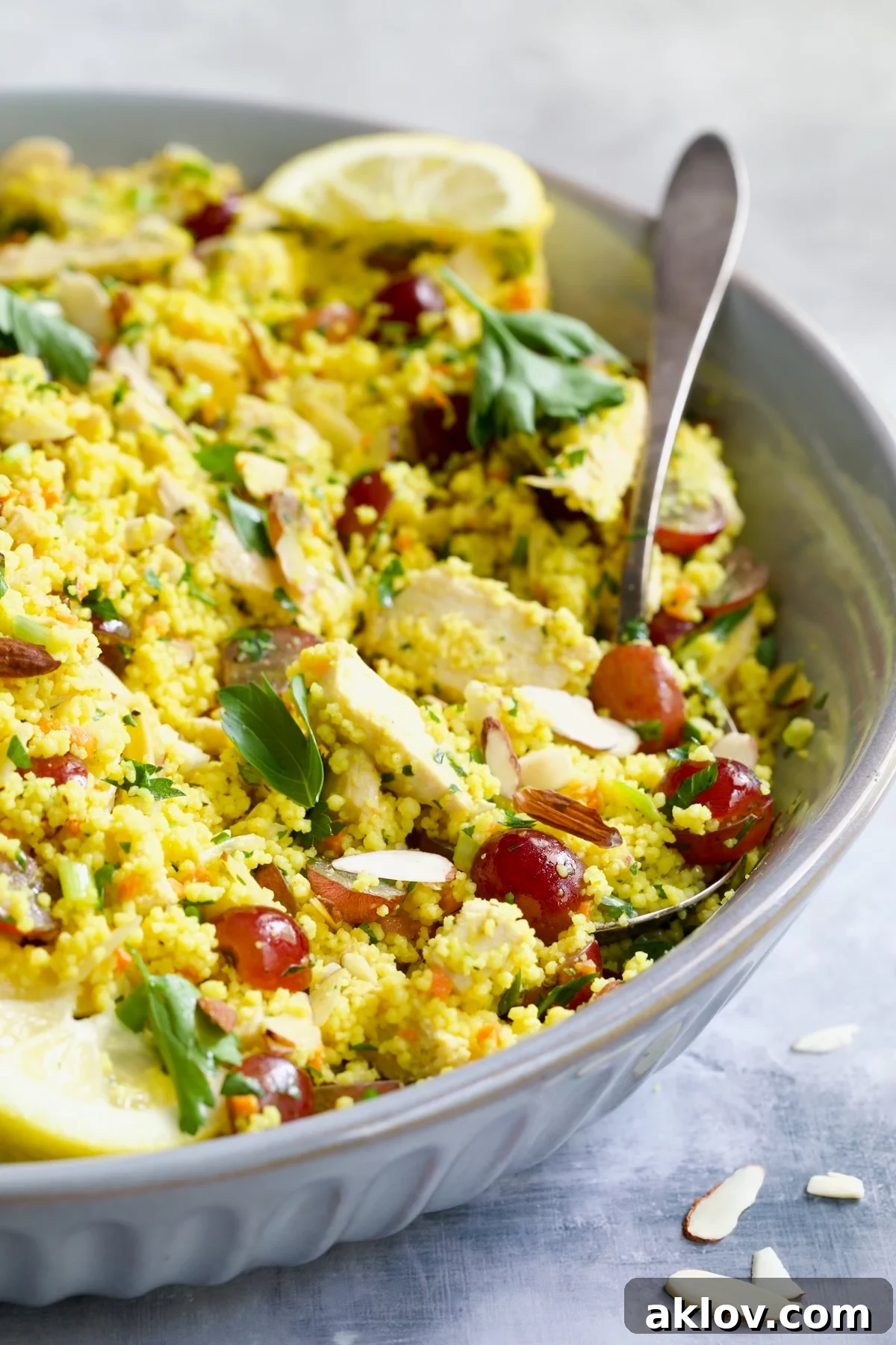 Chicken Couscous Salad in gray bowl with serving spoon.