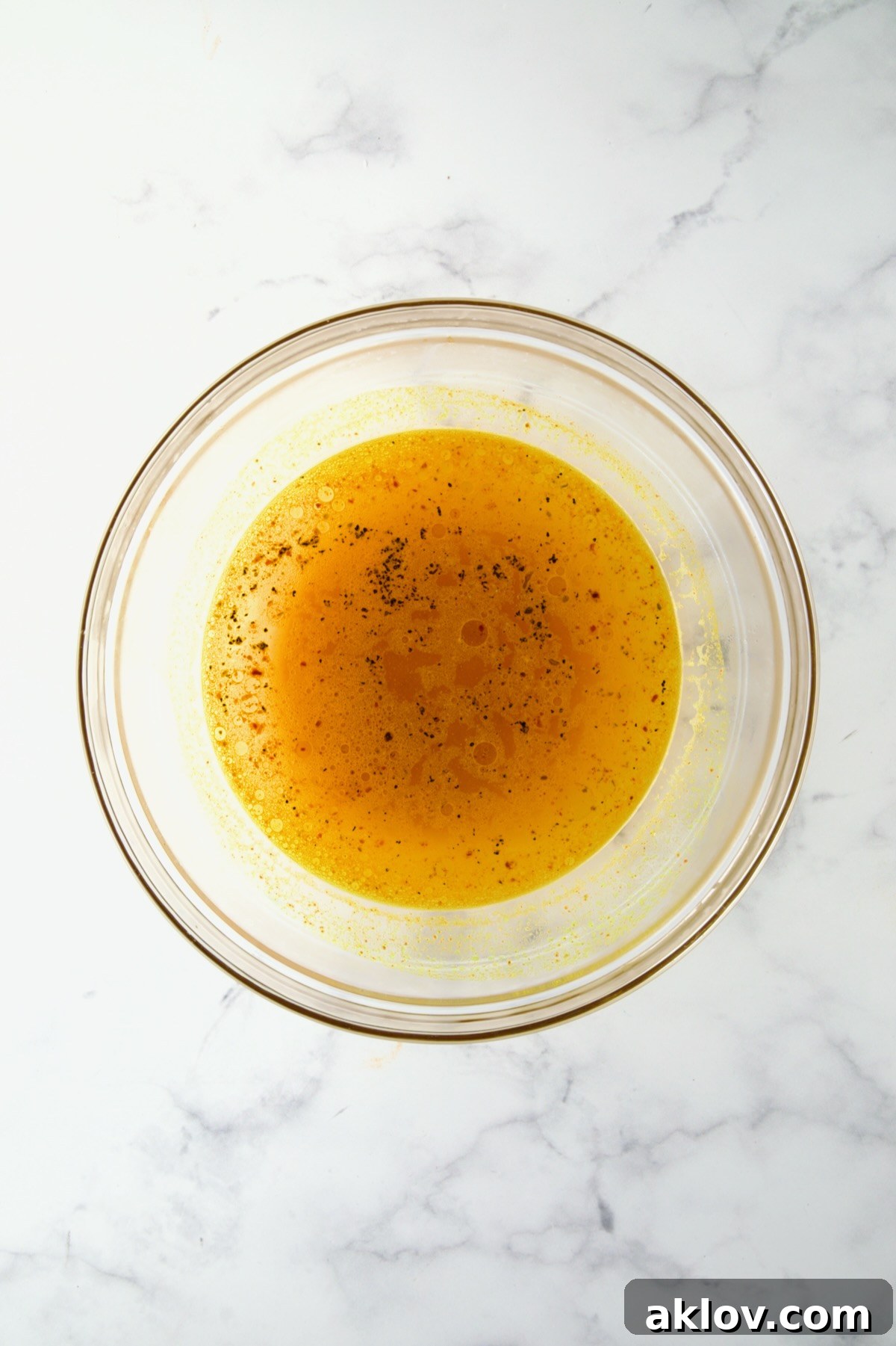 A glass bowl containing boiling water, infused with vibrant turmeric and other seasonings, ready for the couscous.
