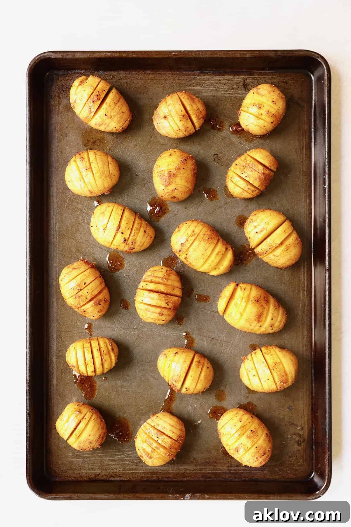 Photo of seasoned hasselbacked potatoes on baking sheet before baking.