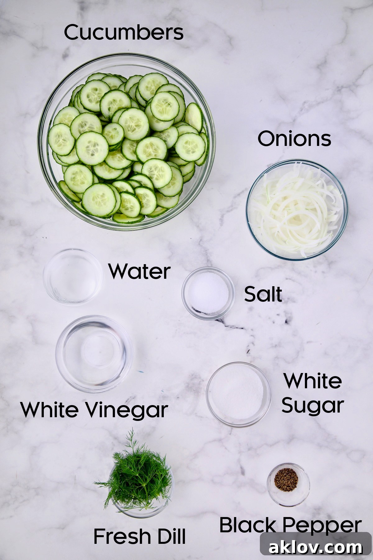 Assortment of fresh ingredients for Cucumber Onion Salad in glass bowls.