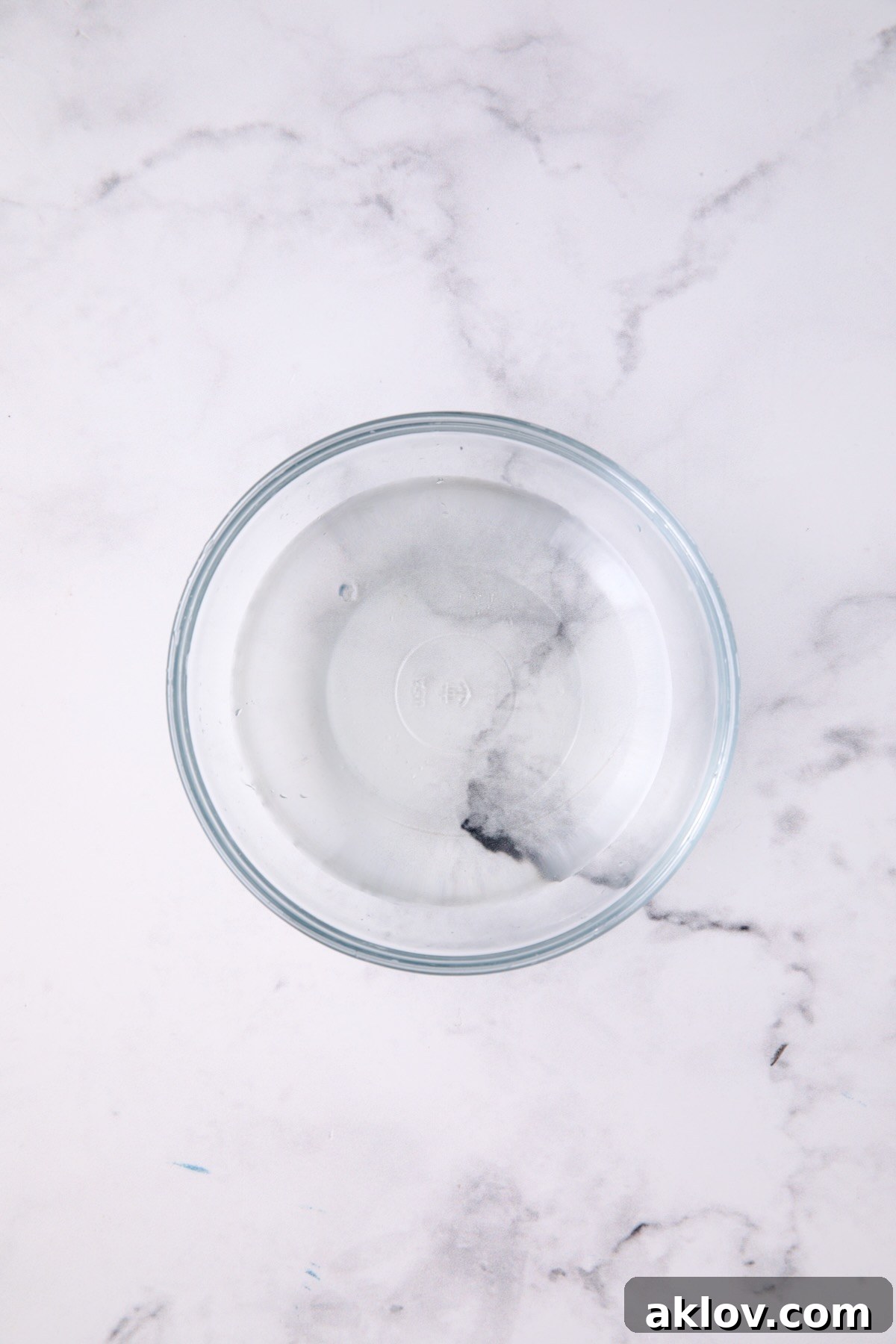 Vinegar, water, and sugar dressing for salad in a clear glass bowl, ready to be mixed.