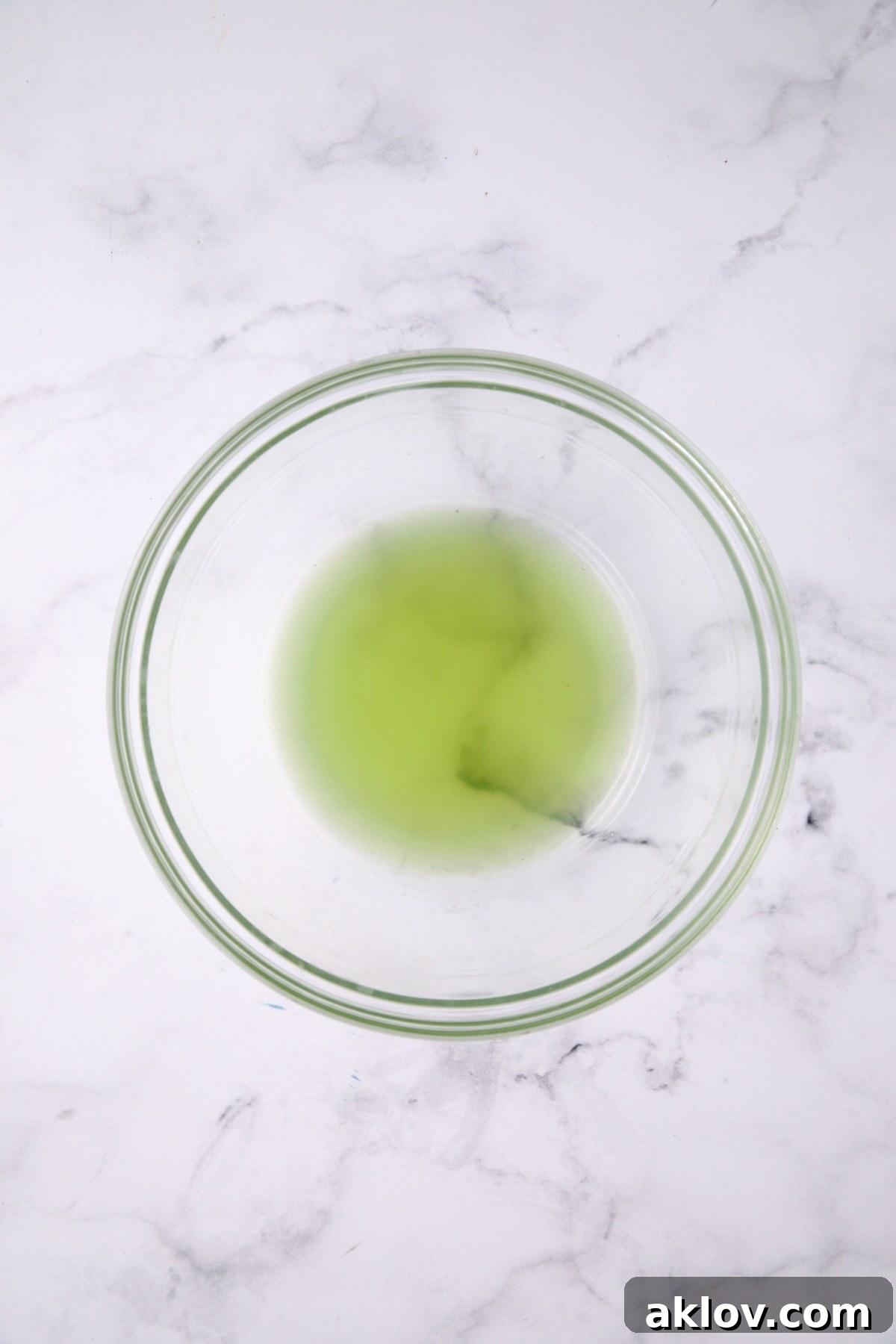 Liquid drained from salted cucumbers in a glass bowl, illustrating the effectiveness of the salting process.