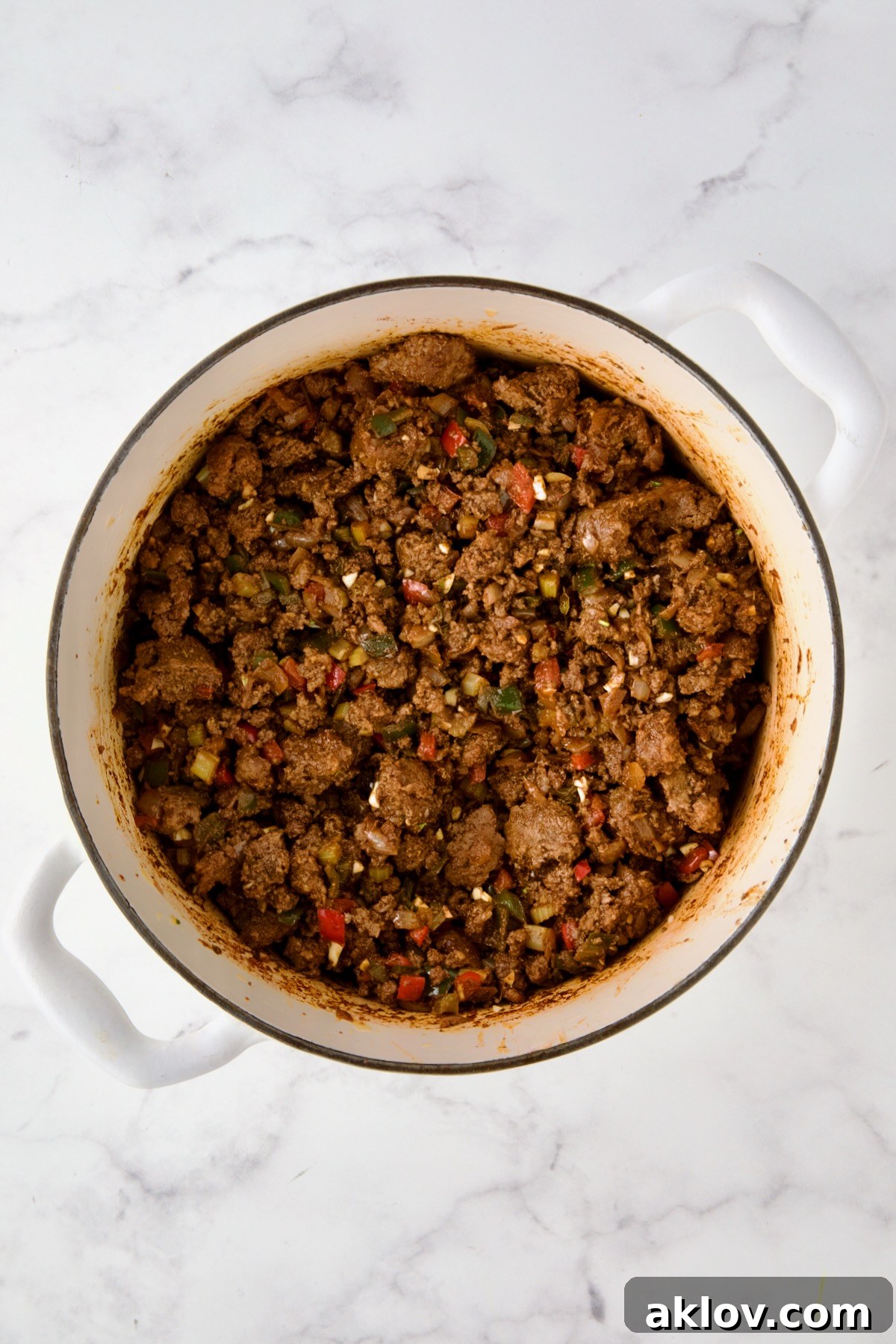 Beef and pork added back to white enamel Dutch oven with spices, vegetables and wine.