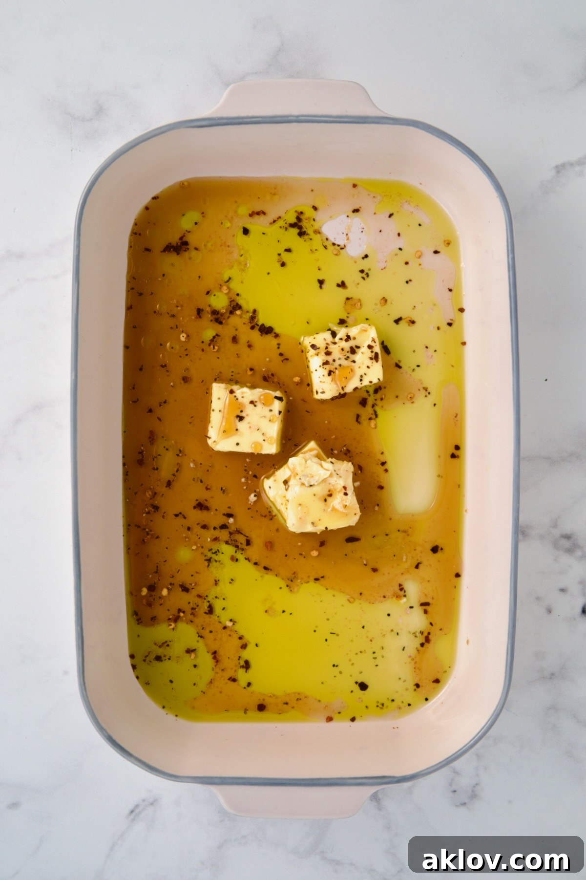 Hot honey glaze ingredients in ceramic rectangular baking dish before butter is melted.