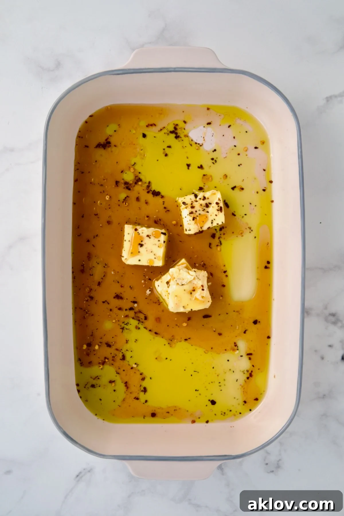 Hot honey glaze ingredients in ceramic rectangular baking dish before butter is melted.
