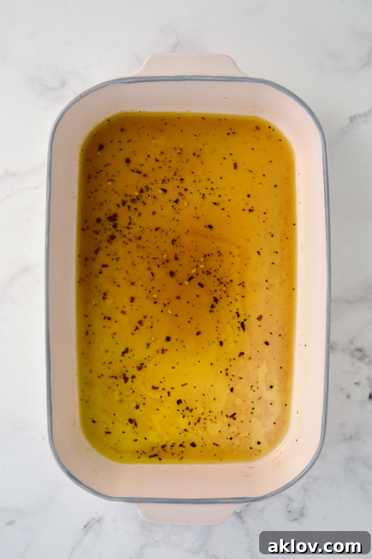 Hot honey glaze ingredients in ceramic rectangular baking dish after butter is melted.