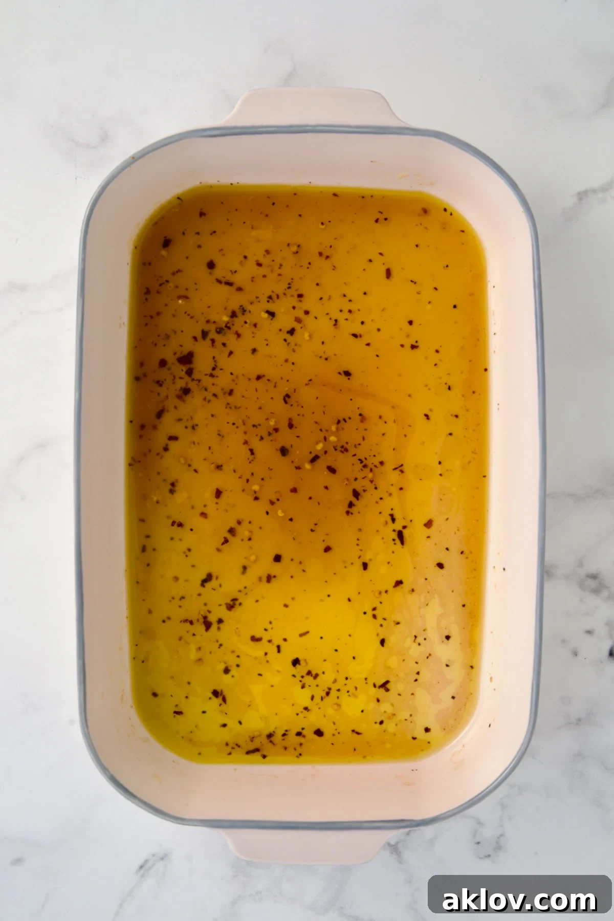 Hot honey glaze ingredients in ceramic rectangular baking dish after butter is melted.