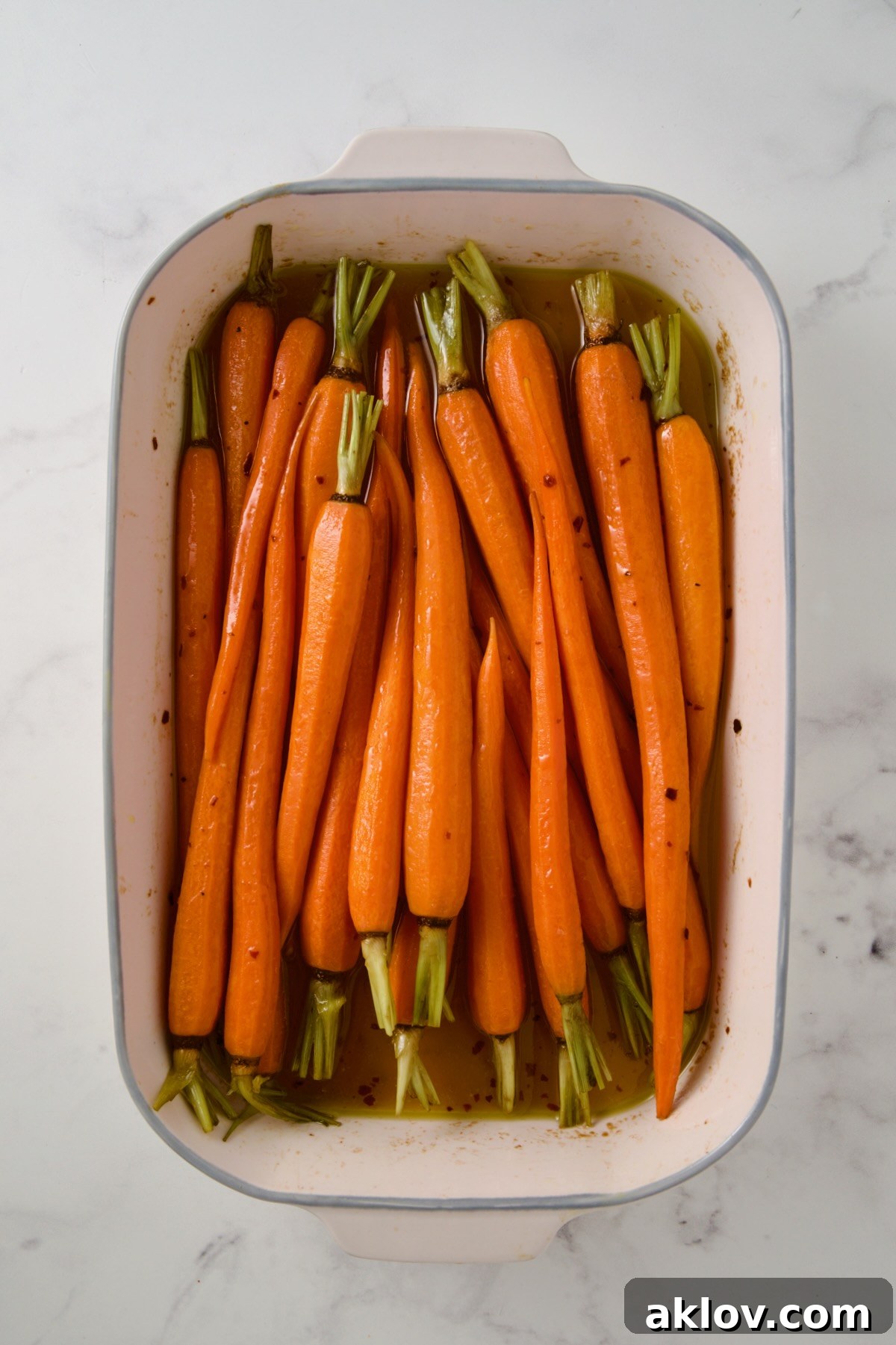 Partially cooked carrots in white rectangle baking dish.