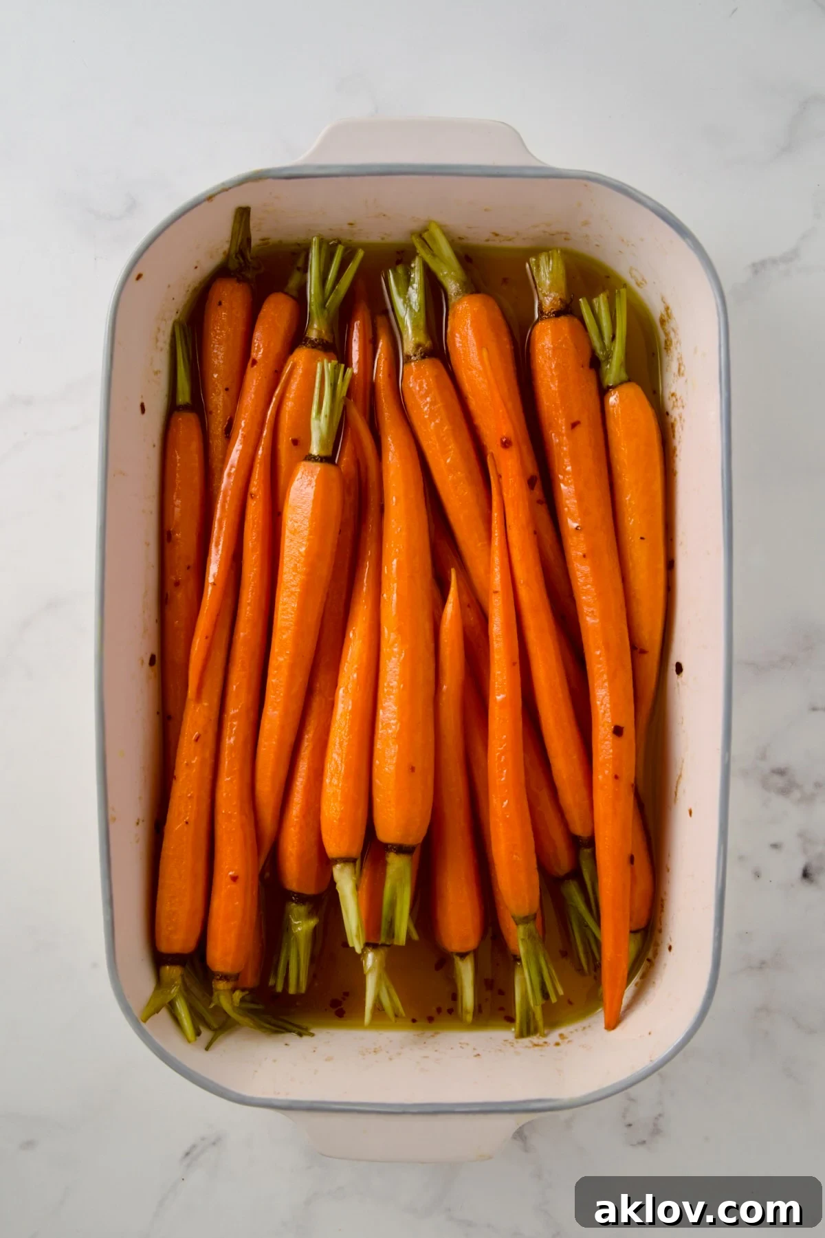 Partially cooked carrots in white rectangle baking dish.