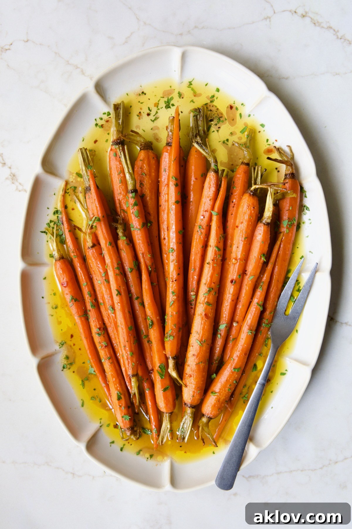 Hot Honey Roasted Carrots on white oval platter with serving fork.
