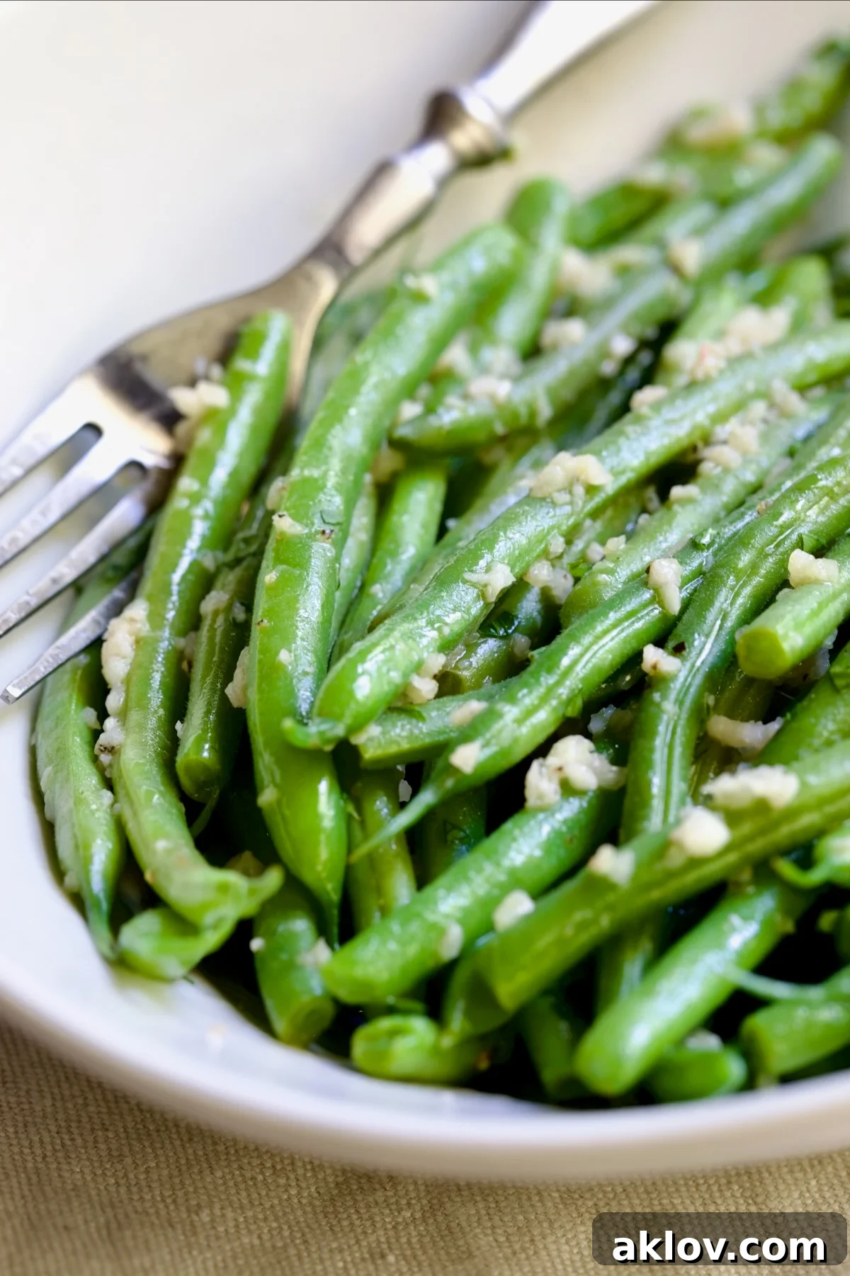 Garlic Green Beans in oval white serving bowl with serving fork.