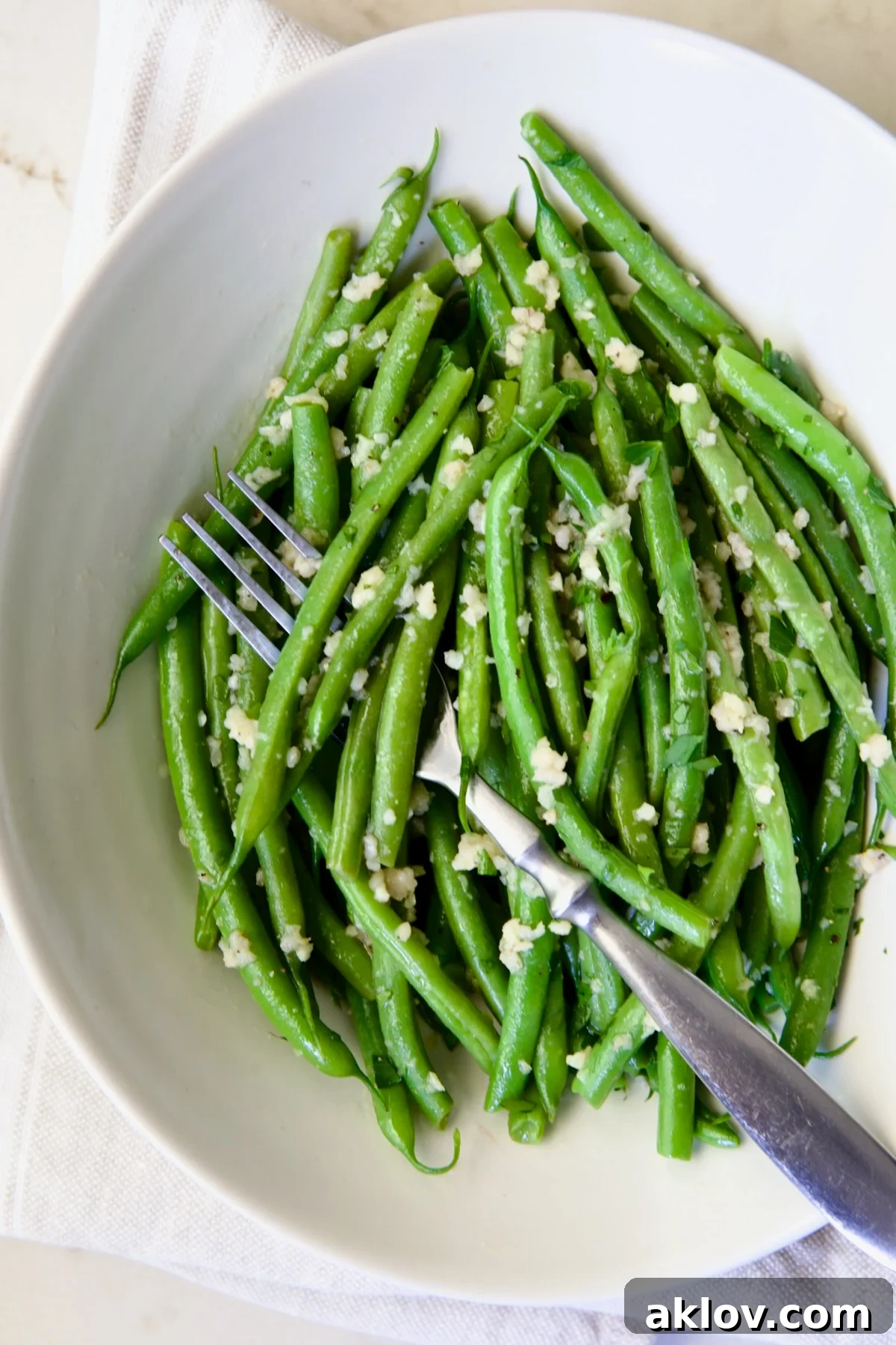 Garlic Green Beans in oval white serving bowl with serving fork.