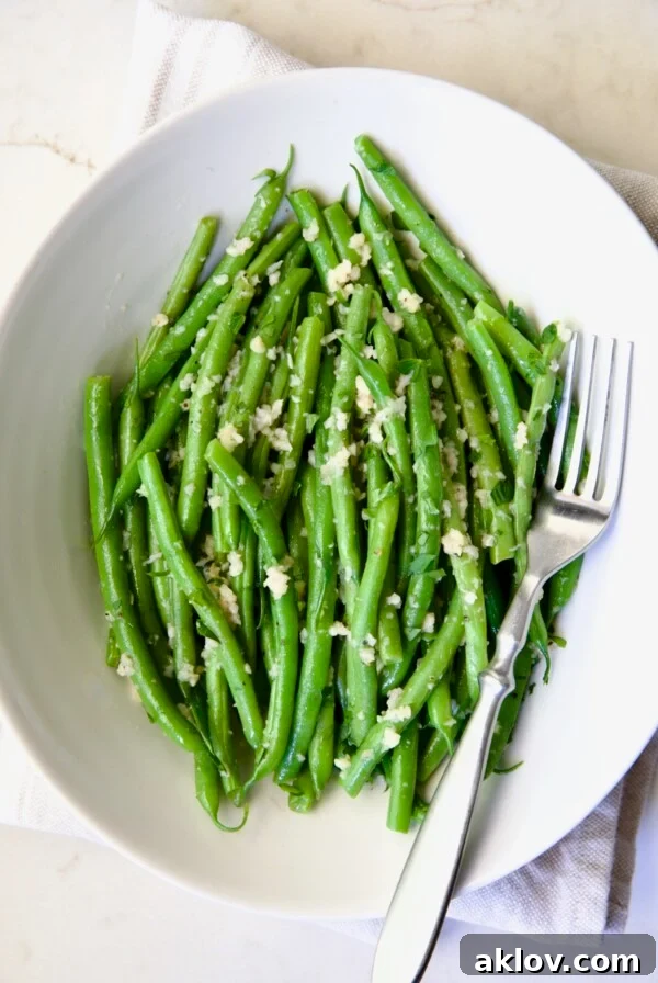 Garlic Green Beans in oval white serving bowl with serving fork.