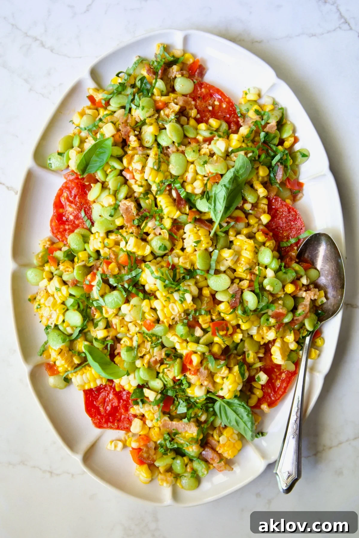Grilled Corn Succotash on white oval platter garnished with fresh basil leaves.