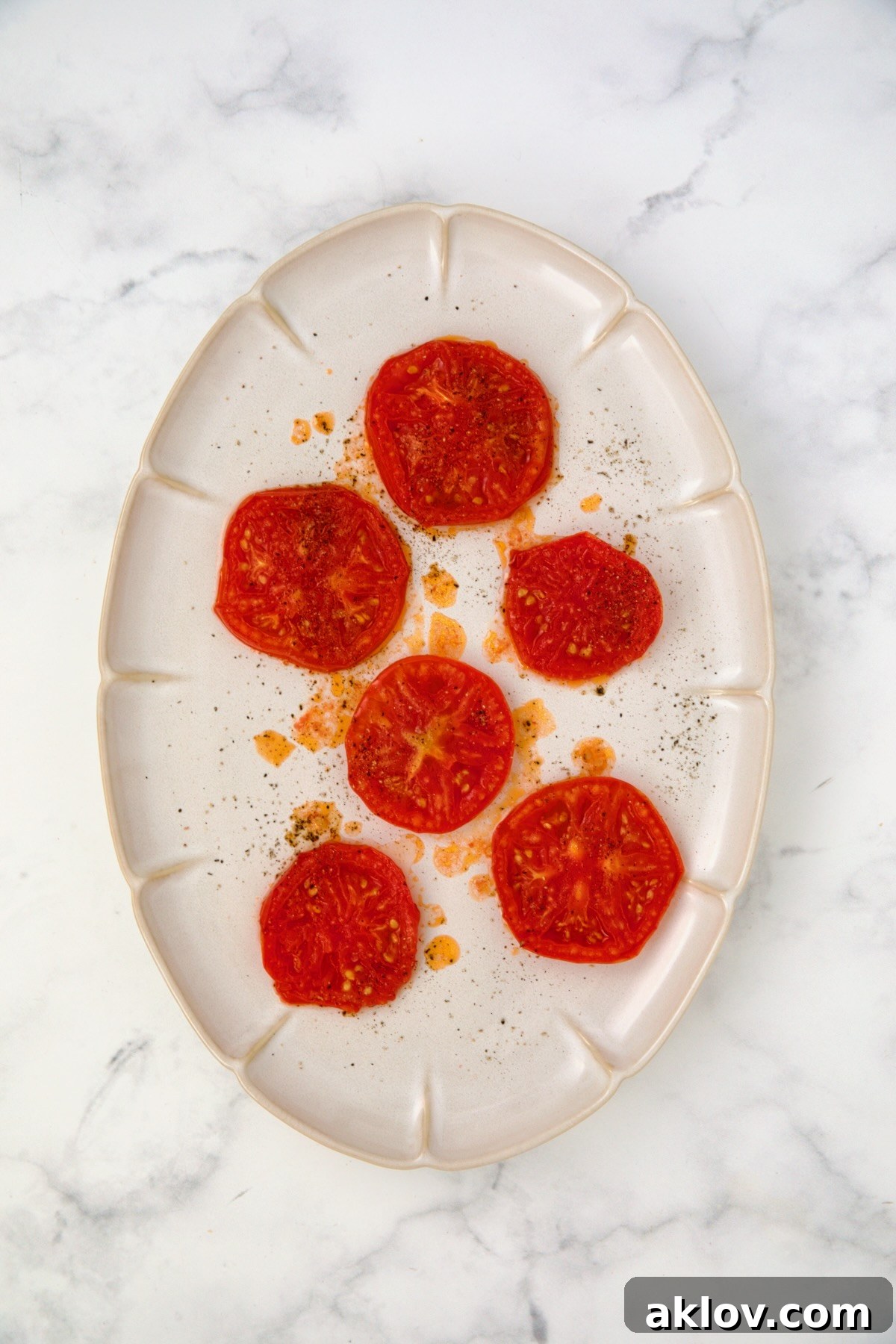 Six grilled tomato slices on white oval platter.