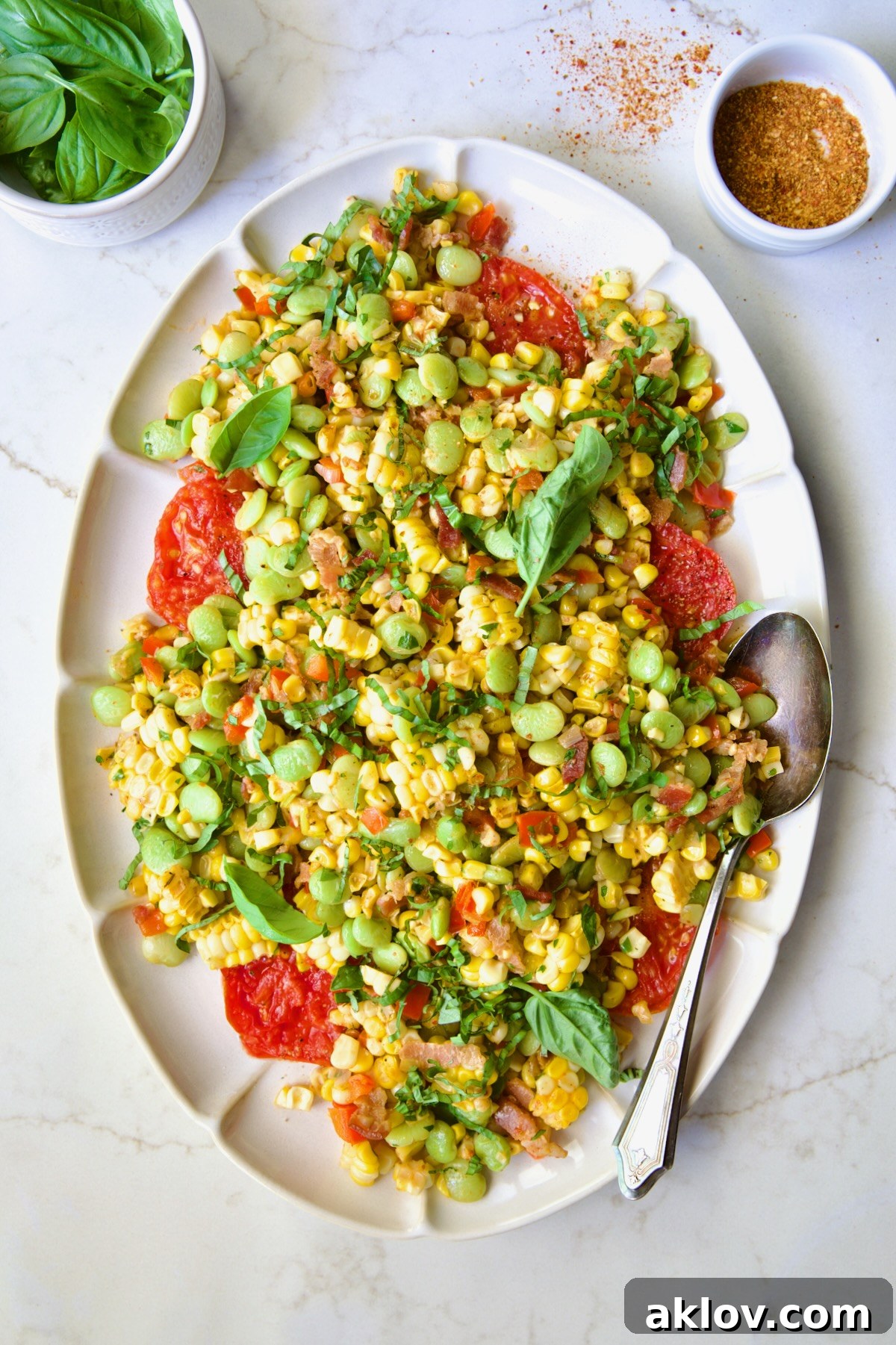 Grilled Corn Succotash on white oval platter garnished with fresh basil leaves.