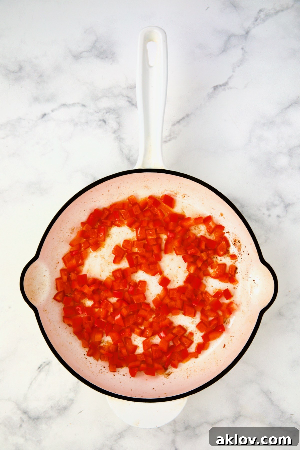 Cooked red bell pepper in white enamel cast iron skillet.