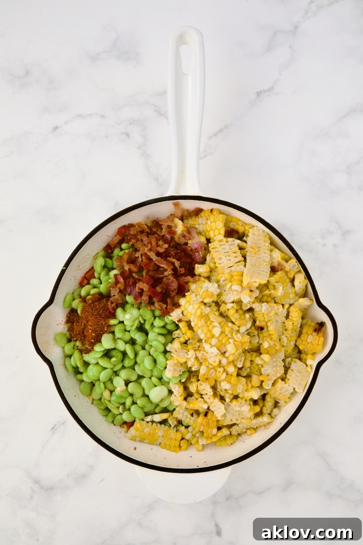 Corn, lima beans and bacon added to red bell pepper and scallion in white enamel cast iron skillet.