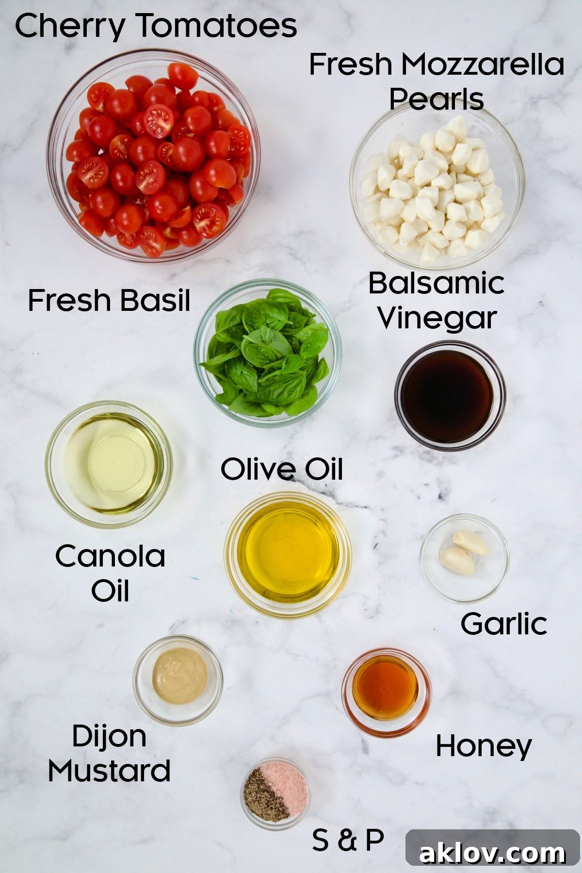 Individual glass bowls holding the fresh ingredients for Caprese Salad: cherry tomatoes, mozzarella pearls, and basil.