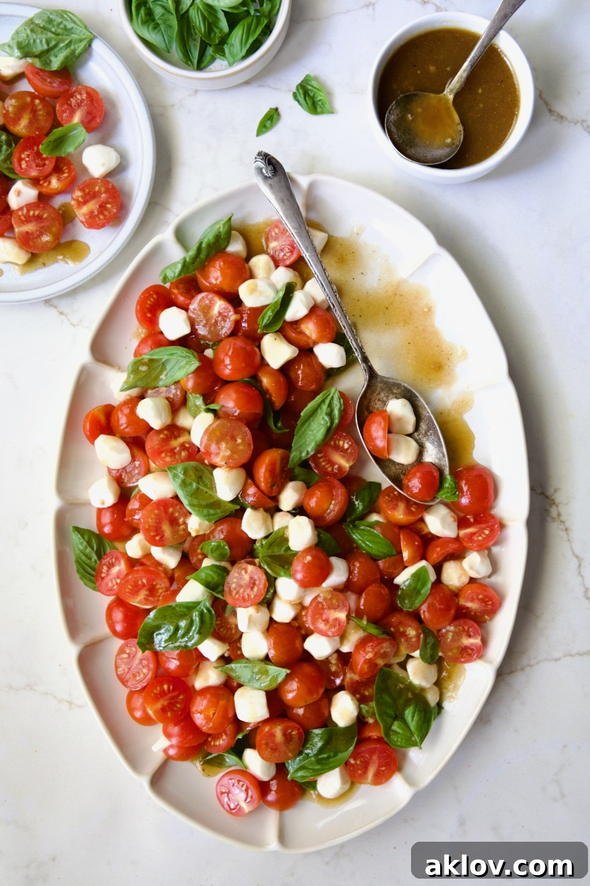 A close-up of Caprese Salad with Cherry Tomatoes, highlighting the fresh ingredients and the appealing texture of the mozzarella, on a white oval platter.