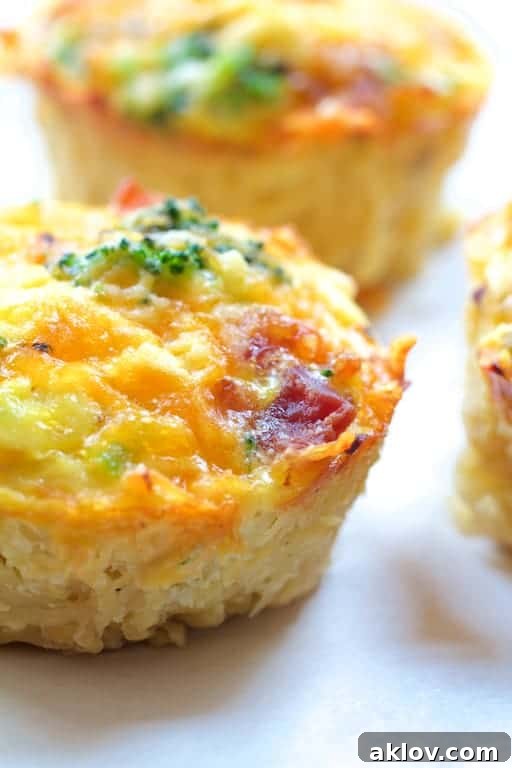 Grab-and-Go Savory Egg Tarts 8 A high-resolution close-up of a single mini quiche, showcasing its tender texture, visible ingredients, and golden-brown top.