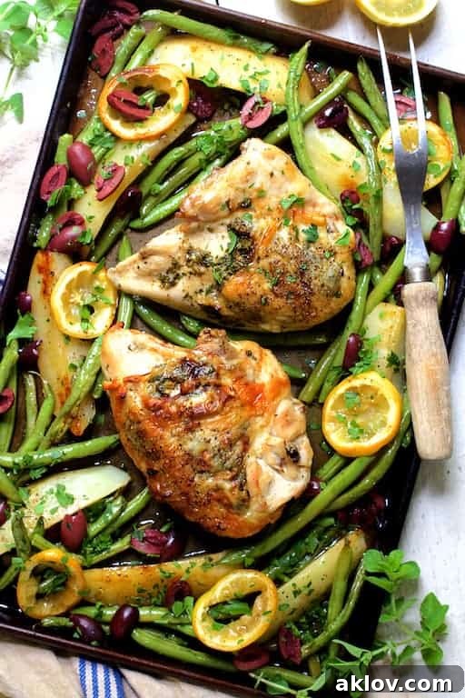 Photo of Sheet Pan Roast Chicken with Potatoes Green Beans Olives and Lemon garnished with fresh oregano.